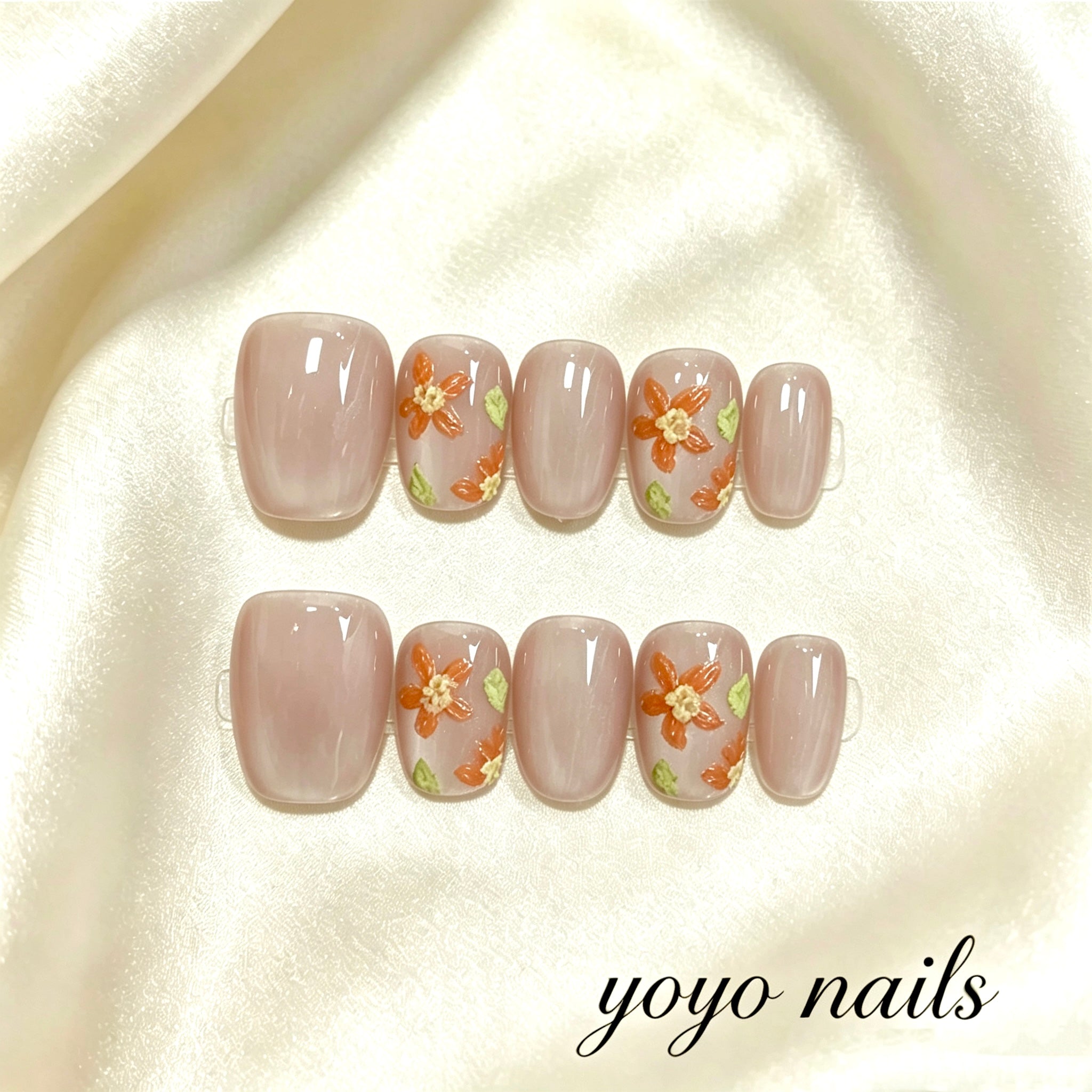 Faux ongles fleurs orange sur fond rose